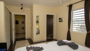 A hotel room with two beds, a bathroom, and a view of the outside. - Trupial G3 Relax & Dive Resort Bonaire Village (Kralendijk)