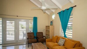 A living room with a sofa, chairs, a coffee table, and a ceiling fan. - Prikichi C2 Relax & Dive Resort Bonaire Village (Kralendijk)