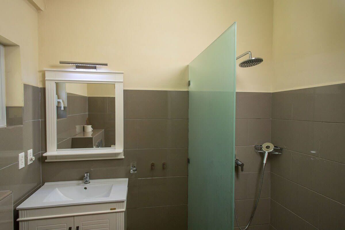 Un baño con lavamanos, espejo y ducha.