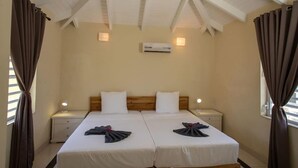 A double room with two beds, a ceiling fan, an air conditioning unit, bedside lamps, and curtains.