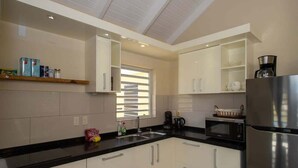 A modern kitchen with white cabinets, a stainless steel refrigerator, a microwave, and a coffee maker.