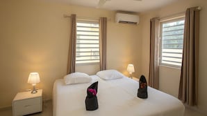 Et hotelværelse med seng, to sengeborde med lamper, en aircondition og en ventilator.