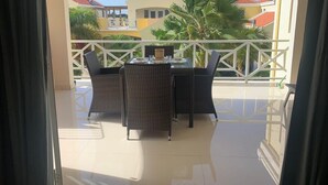 A balcony with a table and chairs, a view of buildings, and a palm tree. - Caracara J1 Relax & Dive Resort Bonaire Village (Kralendijk)