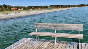 A wooden pier extending into a calm body of water with a bench in the foreground.