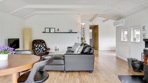 Un vaste espace de vie comprenant une table à manger en bois, un canapé en cuir et une cheminée.