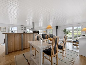 Une cuisine spacieuse avec un îlot central en bois, des chaises modernes et un éclairage suspendu.