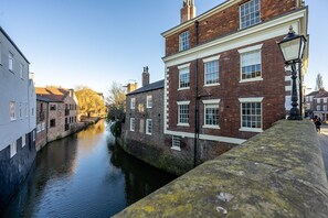 A canal with buildings on either side, including a brick building with white window frames and a lamp post.