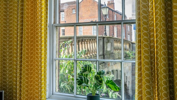 A room with a large window, yellow patterned curtains, and a potted plant on the windowsill. - A family retreat that sleeps 4 guests in 2 bedrooms (York)