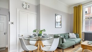 A modern living room with a round glass table, white chairs, a green sofa, and a framed picture on the wall. - A family retreat that sleeps 4 guests in 2 bedrooms (York)