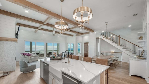 A spacious kitchen with a central island, wooden beams, and large windows offering a view of the ocean. - Coral Cay - A Stunning Home with Exquisite Views! (Inlet Beach)