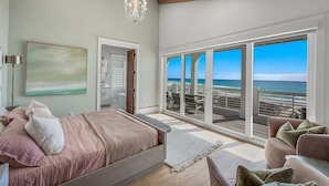 A bedroom with a large bed, a view of the beach, and a balcony with outdoor seating. - Coral Cay - A Stunning Home with Exquisite Views! (Inlet Beach)