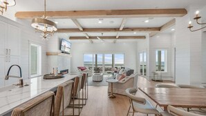 A spacious kitchen with a large island, wooden beams, and a view of the ocean. - Coral Cay - A Stunning Home with Exquisite Views! (Inlet Beach)
