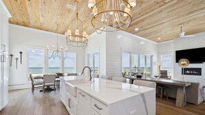 A spacious kitchen with a large island, wooden ceiling, and large windows overlooking the ocean. - Ultimate 8-Bedroom Getaway for Families & Groups (Inlet Beach)