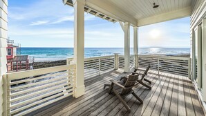 A covered wooden deck with a view of the ocean, a lifeguard tower, and a chair. - Ultimate 8-Bedroom Getaway for Families & Groups (Inlet Beach)