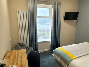 A hotel room with a bed, a desk, a chair, a television, and a window with curtains. - The Balmoral Hotel (Blackpool)