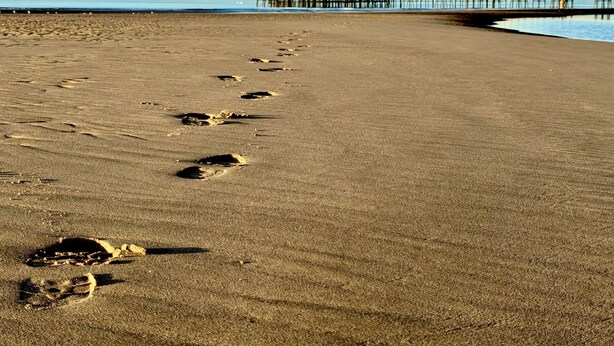 A sandy beach with footprints leading towards a pier with buildings. - The Balmoral Hotel (Blackpool)