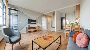 Una sala de estar moderna con un sofá, un sillón, una mesita de centro, televisor y un comedor con mesa y sillas.