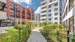 Un patio urbano moderno con un sendero, vegetación y edificios residenciales de varios pisos.