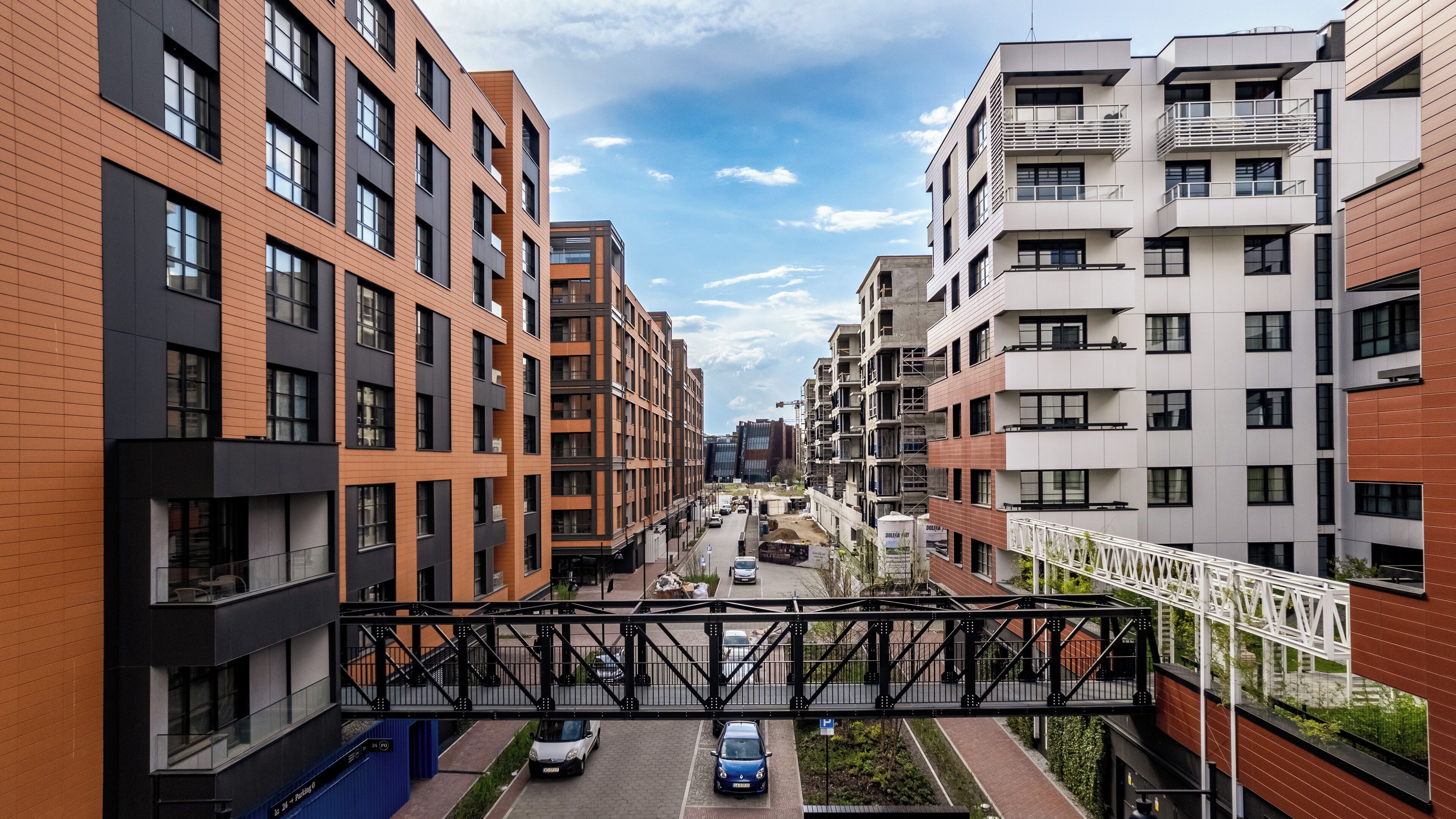 Um moderno complexo de apartamentos urbanos com vários andares, varandas e uma passarela para pedestres.