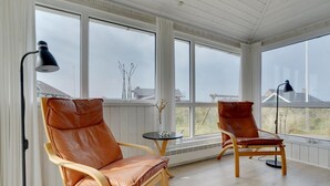 Ein Wintergarten mit zwei Ledersesseln, einem kleinen Tisch und einer Stehlampe.