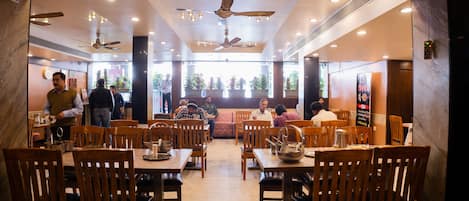A restaurant with wooden tables and chairs, ceiling fans, and a view of the outdoors.