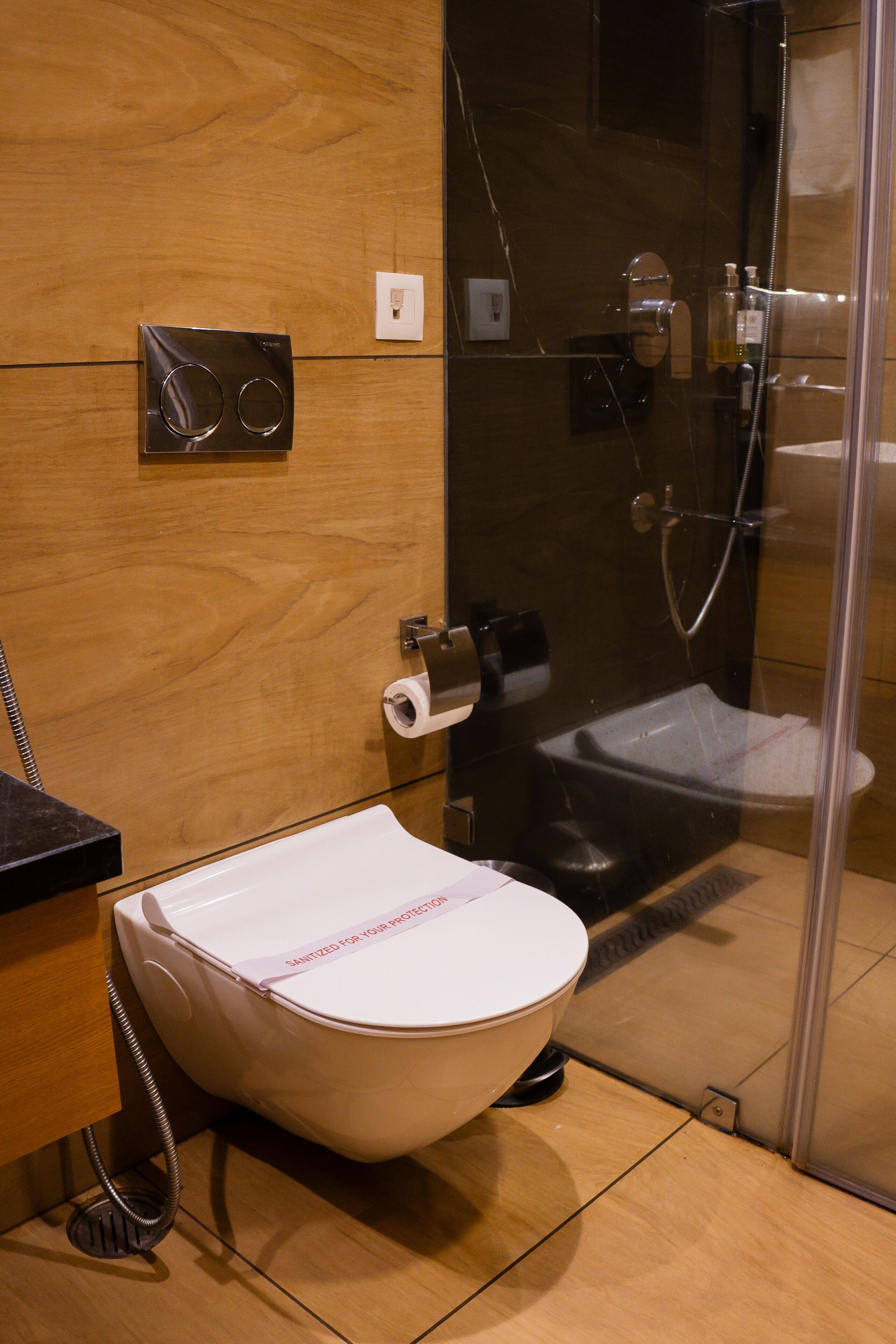 Um banheiro moderno com um design de vaso sanitário único, box de vidro e parede de madeira.