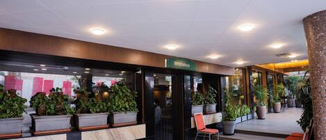 A hotel lobby with a reception desk, seating area, and potted plants.