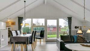 A spacious room with a high ceiling, a dining area with a table and chairs, a sofa, and a fireplace. - "Hortensia" - 350m from the sea by Interhome (Egernsund)