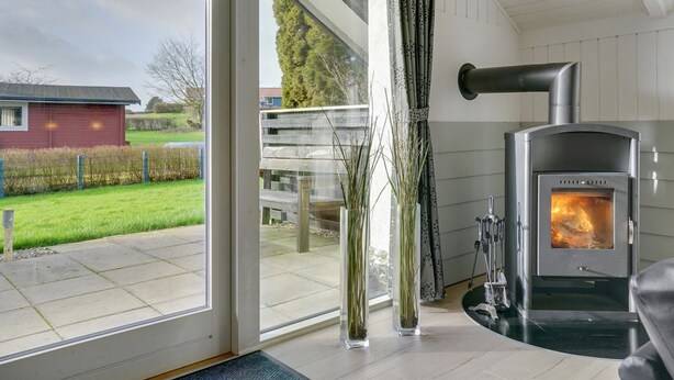 A modern interior with a wood-burning stove, large windows, and a view of the outdoors. - "Hortensia" - 350m from the sea by Interhome (Egernsund)