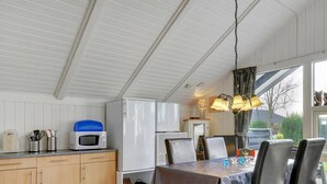 A modern kitchen with wooden cabinets, a microwave, and a refrigerator. There is a dining table with chairs and a chandelier above. - "Hortensia" - 350m from the sea by Interhome (Egernsund)