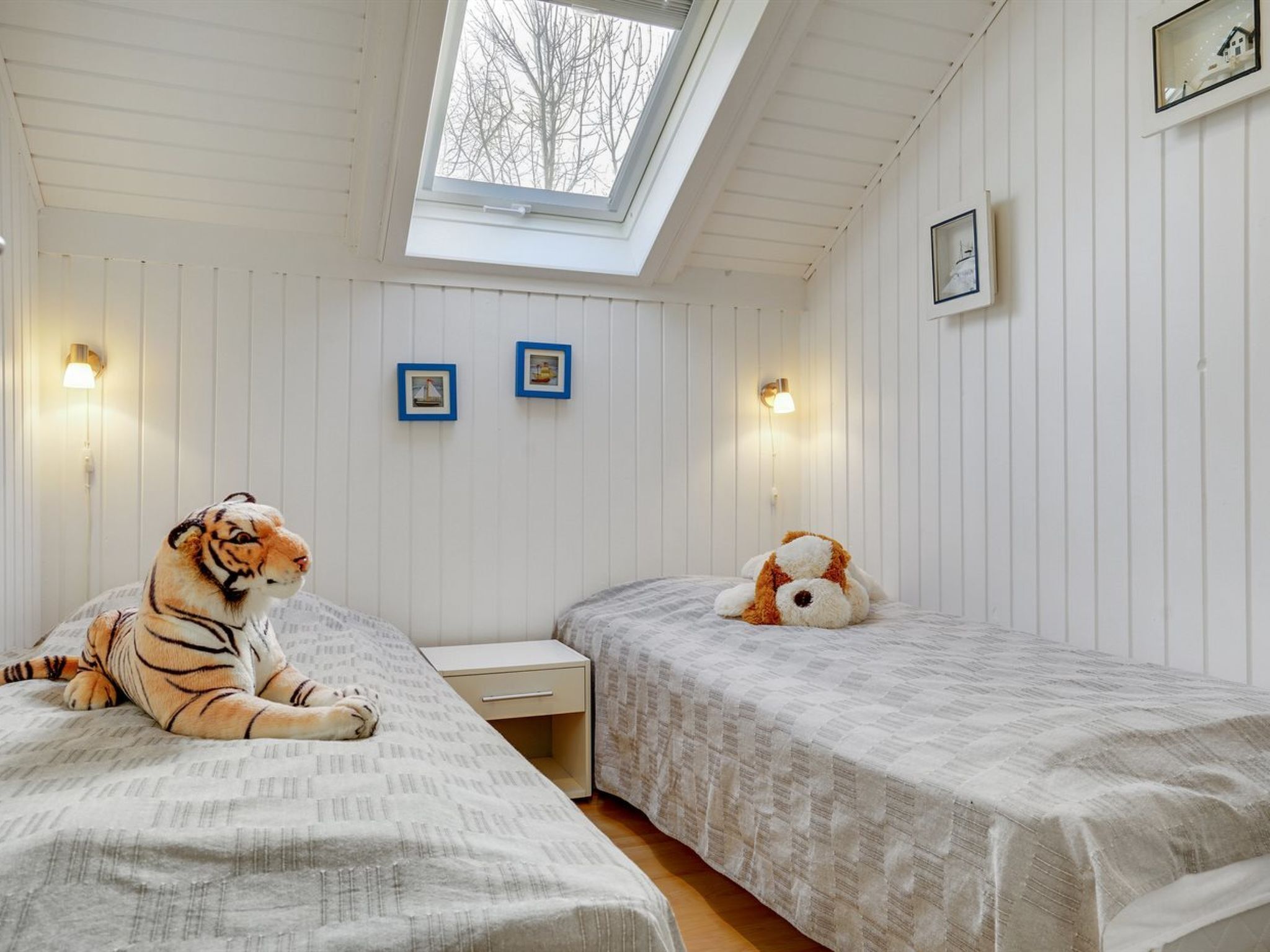 Een slaapkamer met twee bedden, een dakraam en wandlampen.