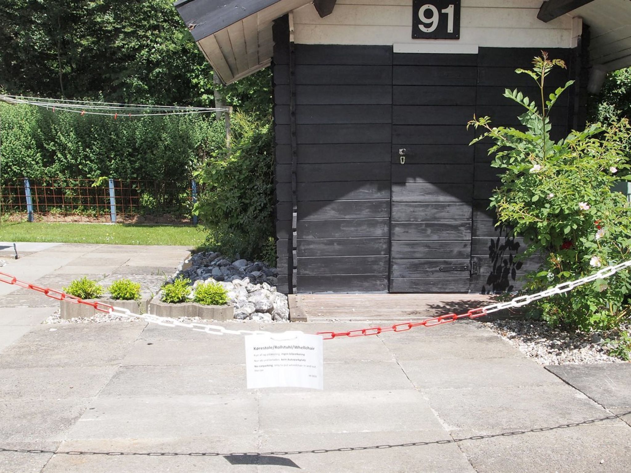 A black building with the number 91, a gated entrance, and a sign indicating a wheelchair-accessible area.