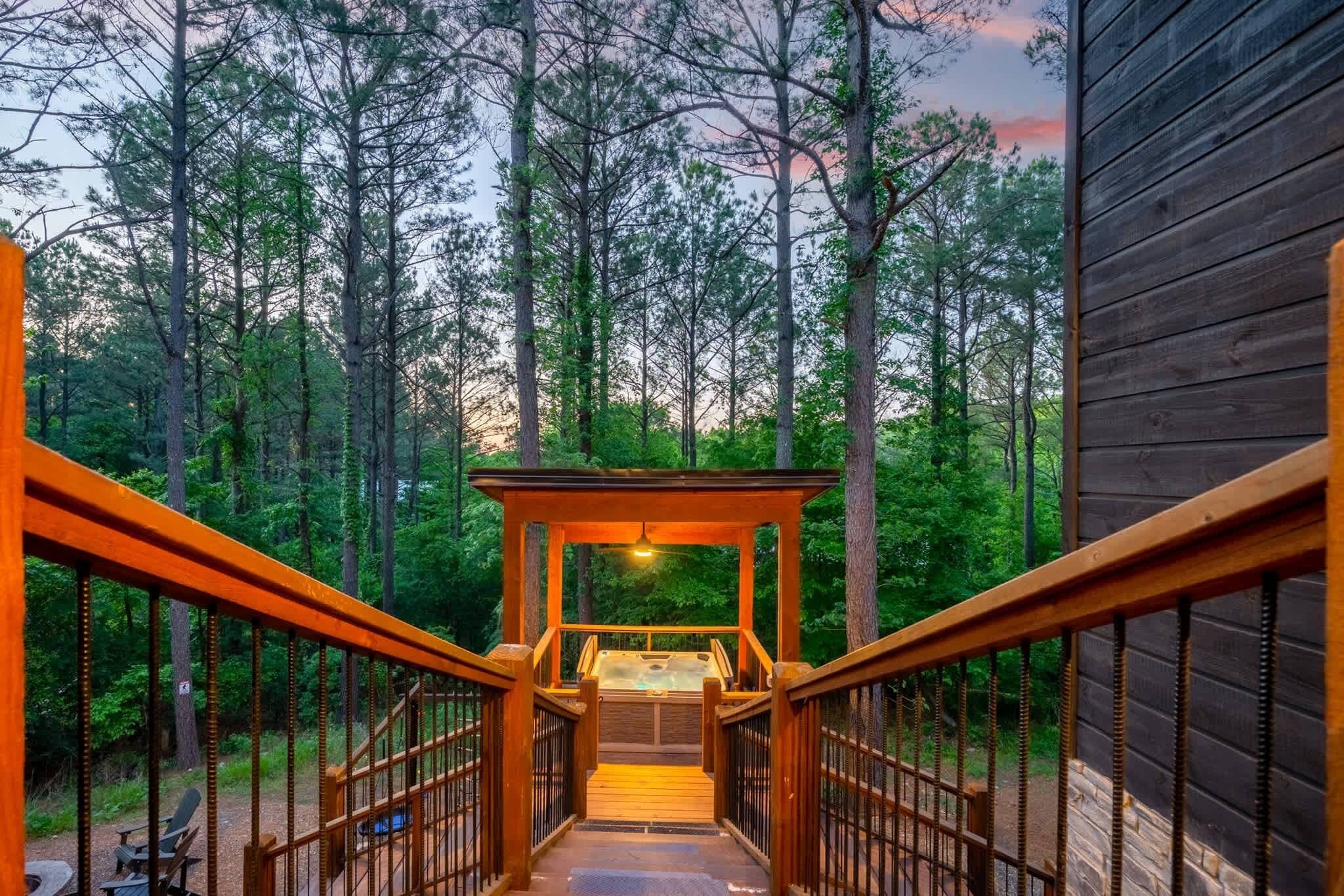 Una escalera de madera que lleva a un jacuzzi en un área boscosa.