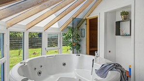 A modern bathroom with a freestanding bathtub, a shower area, and a small shelf with toiletries.