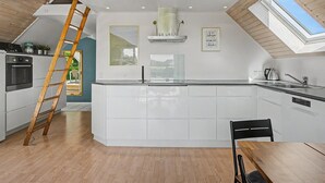 A modern kitchen with a central island, built-in oven, and a skylight.