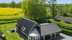 A house with a large garden, a gazebo, and a field in the background.