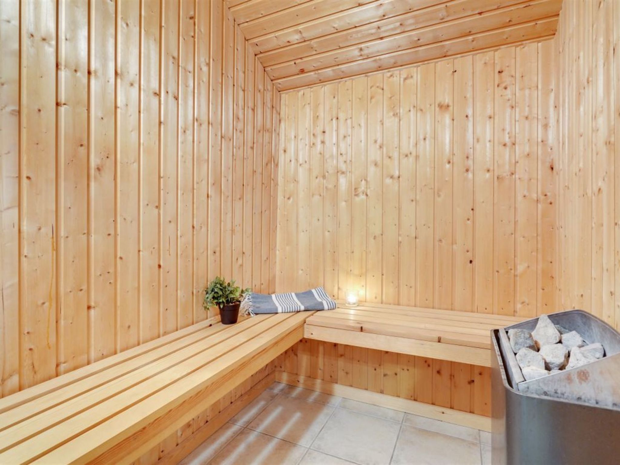 Een houten sauna met banken en een kleine houtkachel.