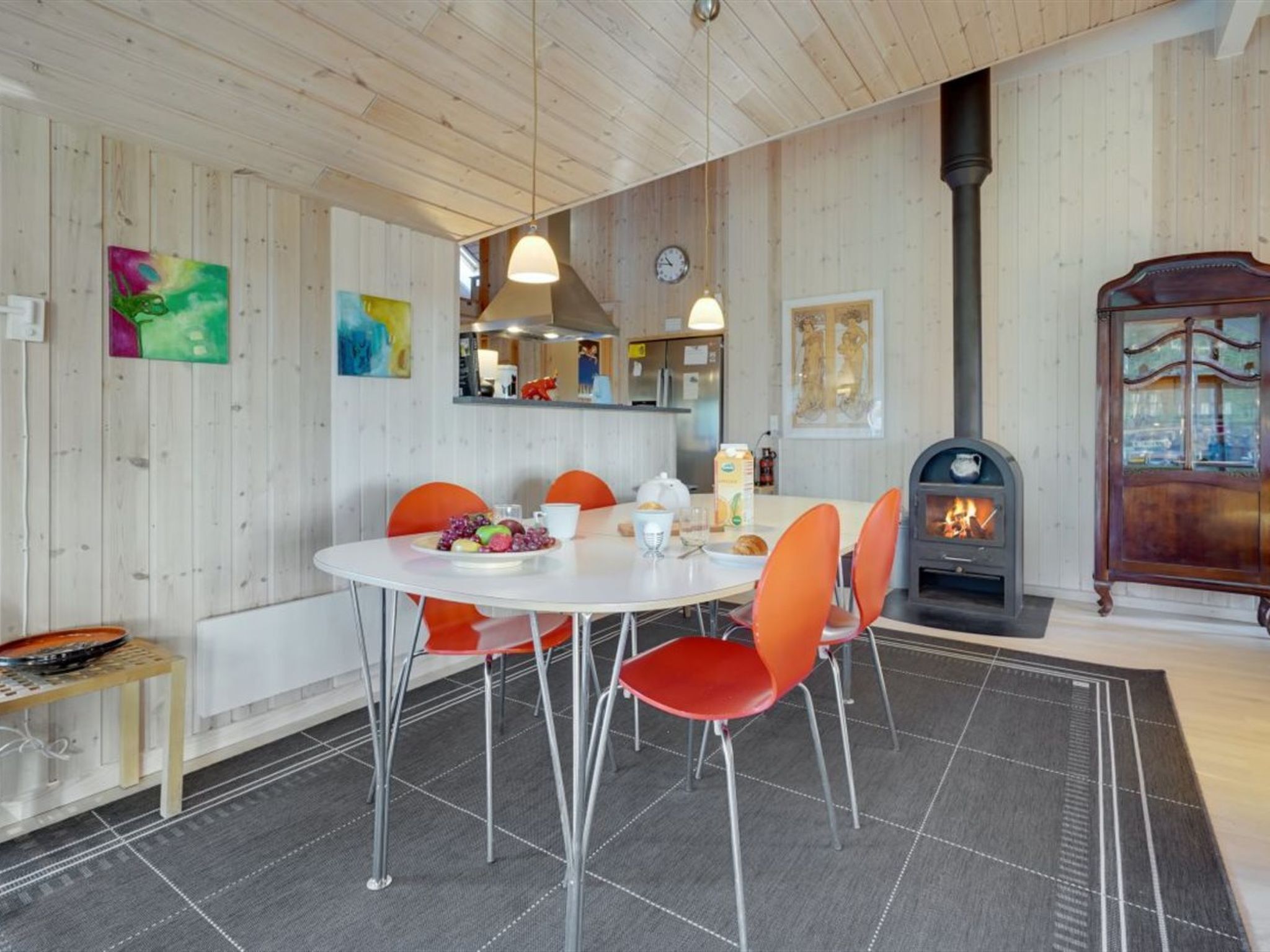 Un comedor acogedor con una mesa redonda, sillas naranjas y una chimenea central.
