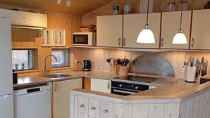 A compact kitchen with wooden cabinets, a microwave, a stove, and a sink.