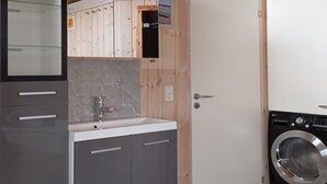 A compact kitchen with a sink, cabinets, and a washing machine.