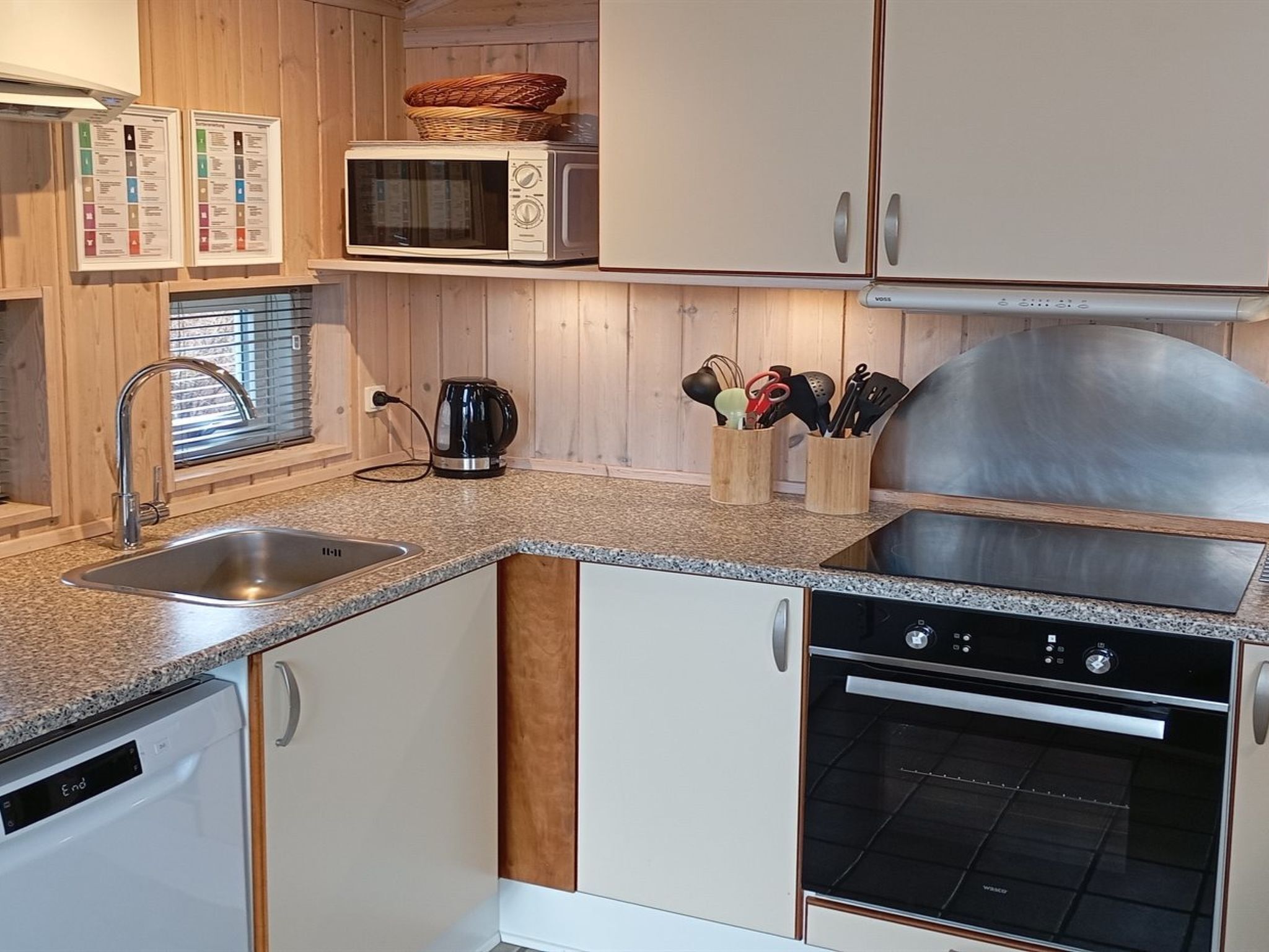 Cucina con mobili in legno, un forno a microonde, un bollitore e una macchina per il caffè.