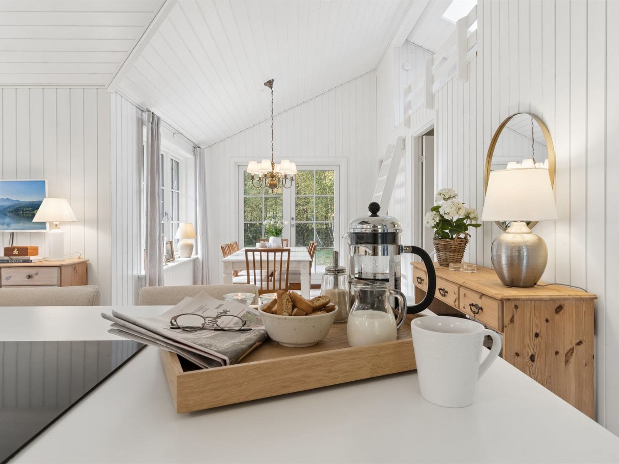 A modern kitchen with a wooden countertop, a coffee maker, a tray with bread, and a mug.
