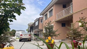 A residential building with a car parked in front, potted plants, and a clear sky. - PREMONT STUDIOS GHIMBAV (Ghimbav)
