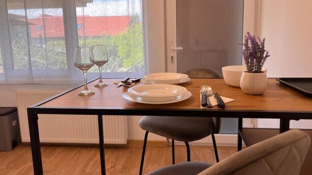 A dining area with a table set for two, two wine glasses, a plate, cutlery, and a potted plant. - PREMONT STUDIOS GHIMBAV (Ghimbav)