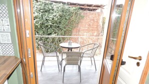 A glass door leading to an outdoor patio with a table and chairs, a brick wall, and a green hedge. - PREMONT STUDIOS GHIMBAV (Ghimbav)
