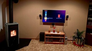 Una sala de estar con chimenea, televisor montado en la pared y una estantería.