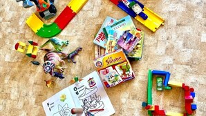 Un área de juegos con distintos juguetes, como bloques de construcción, coches de juguete y una figura de dinosaurio.