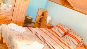 Un dormitorio con una cama de madera, una mesita de noche con lámpara y una ventana con cortinas.