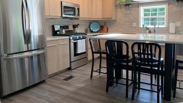 A modern kitchen with stainless steel appliances, wooden cabinets, and a central island with bar stools.