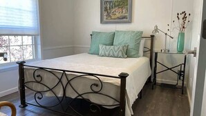 A bedroom with a bed, a nightstand, a lamp, and a painting on the wall.